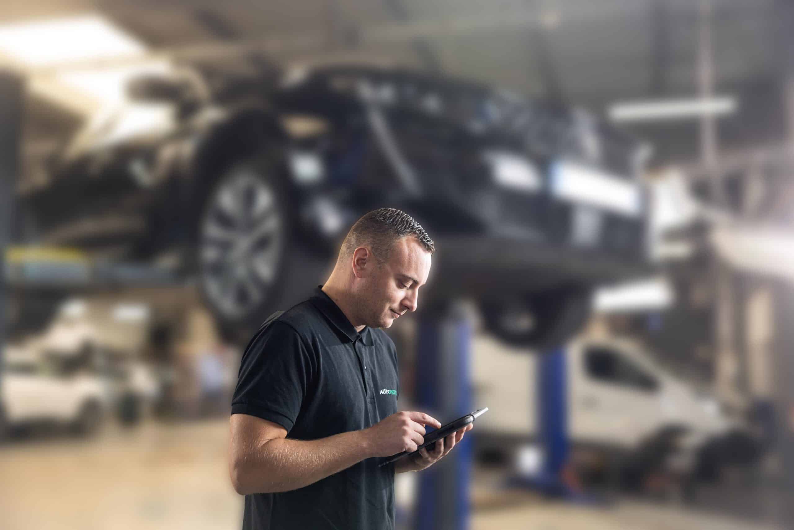 A technician uses a tablet with Progicar software in a garage